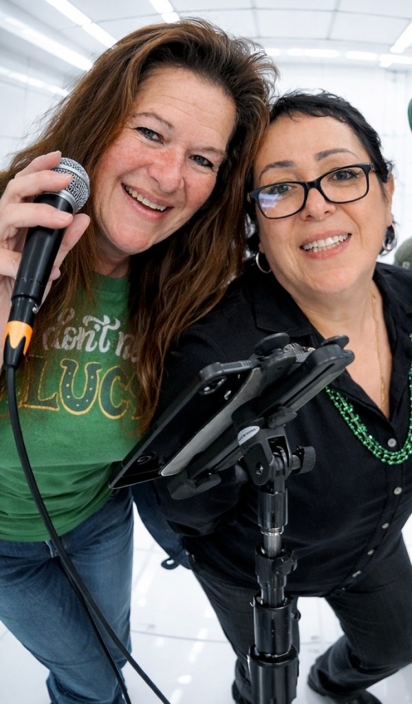 Two band members smiling together near a microphone stand