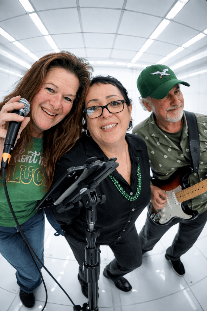 Three band members posing together with microphone and guitar
